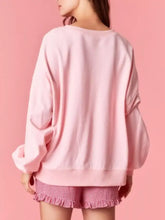 A soft pink oversized bow crew neck sweatshirt with relaxed fit and long sleeves suitable for machine wash cold