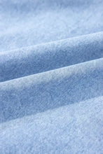 Light blue heathered cotton fabric of a denim dress with spaghetti straps and ruffle hem showcasing soft texture