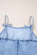 Light blue denim dress with spaghetti straps tied in bows and a ruffle hem with frayed edges