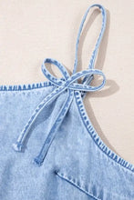 Light blue denim dress with spaghetti straps, ruffle hem, and a tied bow detail at the shoulder