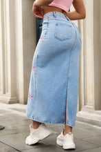 Light blue denim maxi skirt with pink embroidered bows along the side showcasing a stylish denim maxi design