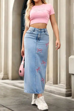 Light blue denim maxi skirt featuring pink embroidered bows for a stylish and casual denim maxi look