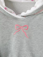A long sleeve hoodie featuring a delicate pink embroidered bow on soft gray fabric with white lace trim