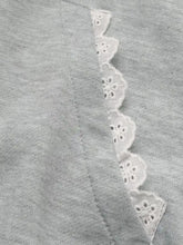 A soft gray long sleeve hoodie features a delicate white lace trim with scalloped edges and intricate eyelet patterns