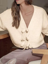 Cream-colored soft-knit long sleeve v-neck cardigan with bow front tie