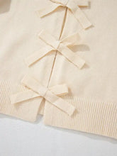 Cream-colored long sleeve cardigan with ribbon bows on front