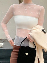 Black quilted handbag with gold heart-shaped clasp paired with bow print sheer mesh top featuring white bow embroidery