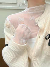 Bow print sheer mesh top in white featuring delicate white bow embroidery worn under a cream ribbed cardigan