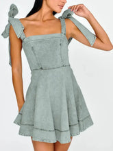 Light blue denim mini dress with square neckline, tied shoulder bows, and slightly stretchy fabric for comfort