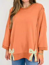 Coral-colored bow slit round neck sweatshirt with delicate light green lace bows and slightly stretchy fabric care instructions machine wash