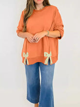 Bow slit round neck sweatshirt in soft orange with decorative lace bows and slightly stretchy fabric, care instructions machine wash