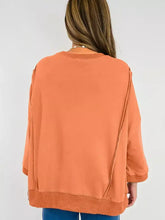A soft rust-orange bow slit round neck sweatshirt with ribbed cuffs, hem, and slightly stretchy fabric, care instructions machine wash