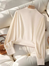 Cream-colored bow tie long sleeve blouse with puffed sleeves and high neckline in lightweight fabric