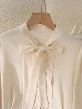 Cream-colored satin bow tie long sleeve shirt with a delicate bow at the neckline for elegant wear