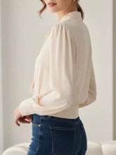 Cream-colored satin bow tie long sleeve shirt with puffed sleeves and a soft flowing silhouette