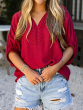 A vibrant red half sleeve blouse featuring intricate cable knit embroidery and a v neck in a loose fit design