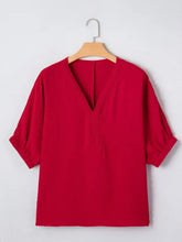 A vibrant red half sleeve blouse with braided detail v-neckline and subtle embroidery on the front
