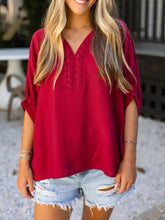 A vibrant red half sleeve blouse with v-neck and intricate braided embroidered detailing on the front