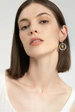 Woman modeling brass contrast cross dangle earrings with gold center