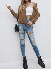 Brown corduroy bomber jacket with gold buttons, zipper details, pockets, distressed blue jeans, black ankle boots