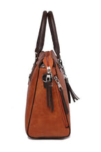 Brown leather bag set with dark handles and tassel charm