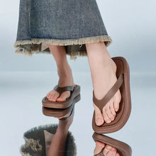 Person in denim skirt wearing brown toe post flats slippers