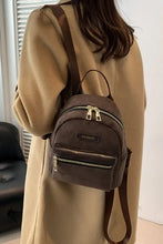 Brown suede adjustable strap mini backpack with gold hardware on beige coat