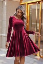 Woman in burgundy velvet knee length dress with round neck