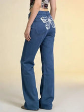 Back side of blue denim butterfly back wide leg jeans featuring white butterfly embroidery on back pocket