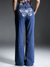 Blue denim wide leg jeans with white butterfly embroidery on the back pocket showing the back side view
