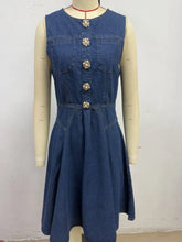 A sleeveless denim dress in blue with floral button closures and front pockets button decor sleeveless denim dress