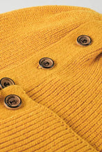 Close-up of mustard yellow ribbed knit cuff beanie with brown buttons