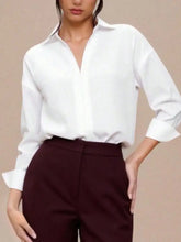 White long sleeve bodysuit with a relaxed fit, button-down front, rolled cuffs, and satin-like finish