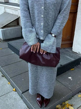 Burgundy leather clutch with padded design in cardigan skirt set