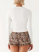 White long-sleeve crop top with moderate stretch paired with leopard print ruffled shorts
