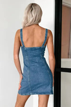 Back view of a fitted blue denim mini cami dress with thin straps and a backless design button down mini cami denim dress