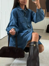 Dark brown suede handbag with rounded top handles and gold-tone buckle detail paired with a mini denim dress