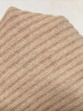 A soft beige ribbed knit scarf made of slightly stretchy material paired with a button-front drawstring hoodie