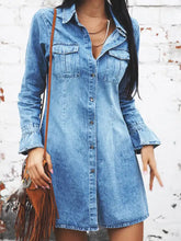 A medium-wash blue denim dress with button-front closure, flared long sleeves, and two chest pockets