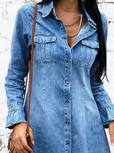 A medium-wash blue button front long sleeve denim dress with chest pockets and button closure