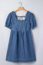 A denim dress with a square neckline, puff sleeves, and button-front detailing in puff sleeve denim style