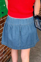 Button-front ruffle hem denim skirt in blue with white stitching paired with a red ribbed top