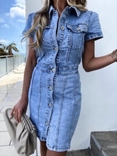 A light blue short sleeve denim dress with button front closure and two chest pockets made of denim material