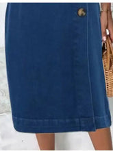 Navy blue denim skirt with a gold-toned button at the waistband featured in a sleeveless denim dress