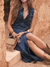 Tan suede fringe crossbody bag with gold-tone studs and top handle styled with sleeveless denim dress