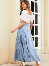 A flowing light blue denim dress with button front and tiered ruffles showcasing classic tiered denim style