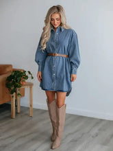 A blue denim dress with a collared neck long sleeve design, button-down front, and belted waist detail