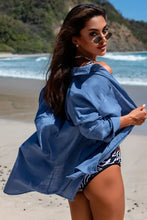 Woman in blue longline shirt with breast pockets and patterned bikini bottoms