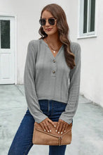 Woman in buttoned notched neck long sleeve T-shirt with jeans and clutch