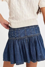 Blue denim mini skirt with buttoned front, gathered waist, and flared ruffled hem perfect for casual wear